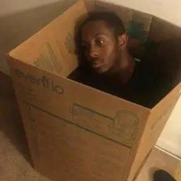 Black man in cardboard box thinking