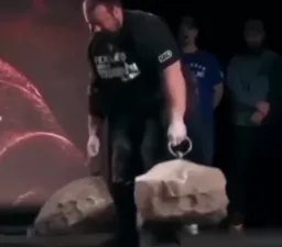 مرد ورزشکار در حال بلند کردن سنگ بزرگ