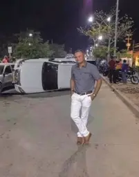 Man posing in front of flipped car