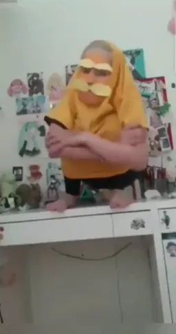 An old man with a yellow hoody falling out of the desk