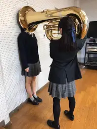 Girl Putting Tuba On Girls Head